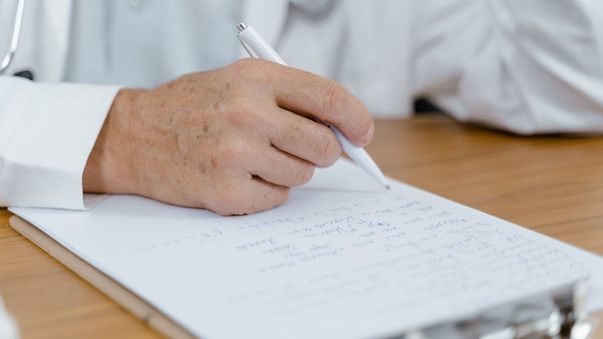 Main écrivant des notes au stylo pour recenser les préjudices d'une victime